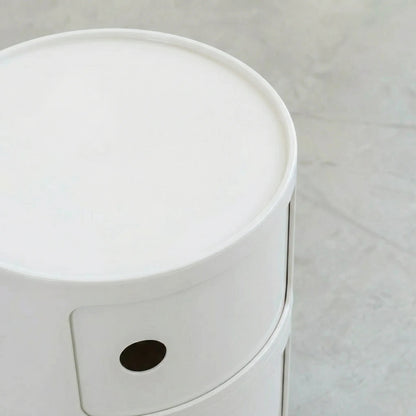 Detail van rond modulair opbergmeubel in wit, op een betonnen vloer.