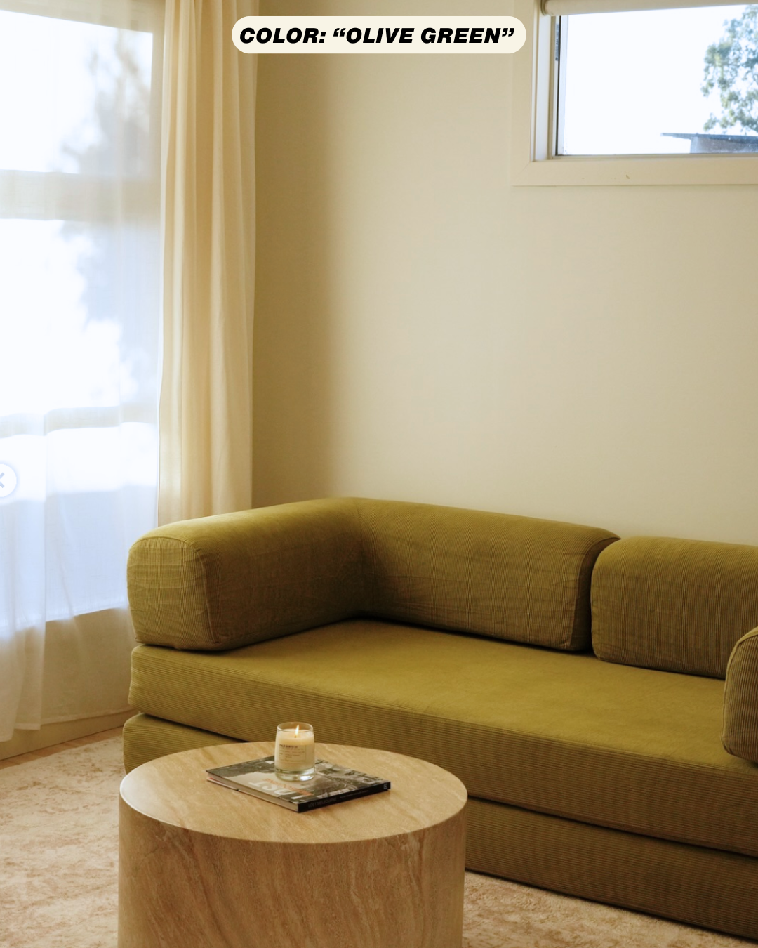 Green teddy sofa alternative in a room with a wooden table and a candle.