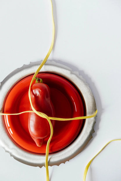 Chunky red ceramic plate inspired by Gustaf Westman in a industrial setting with natural light