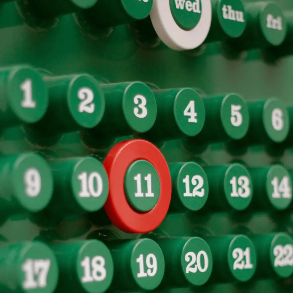 Close-up of a green Ring-a-Date style perpetual calendar dupe with red circle marking the 11th day, inspired by Giorgio Della Beffa design.