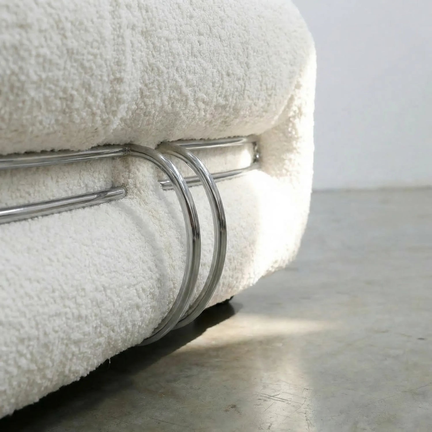 Close-up of a Soriana Chair Dupe in white boucle with a metal rack on a light gray surface.