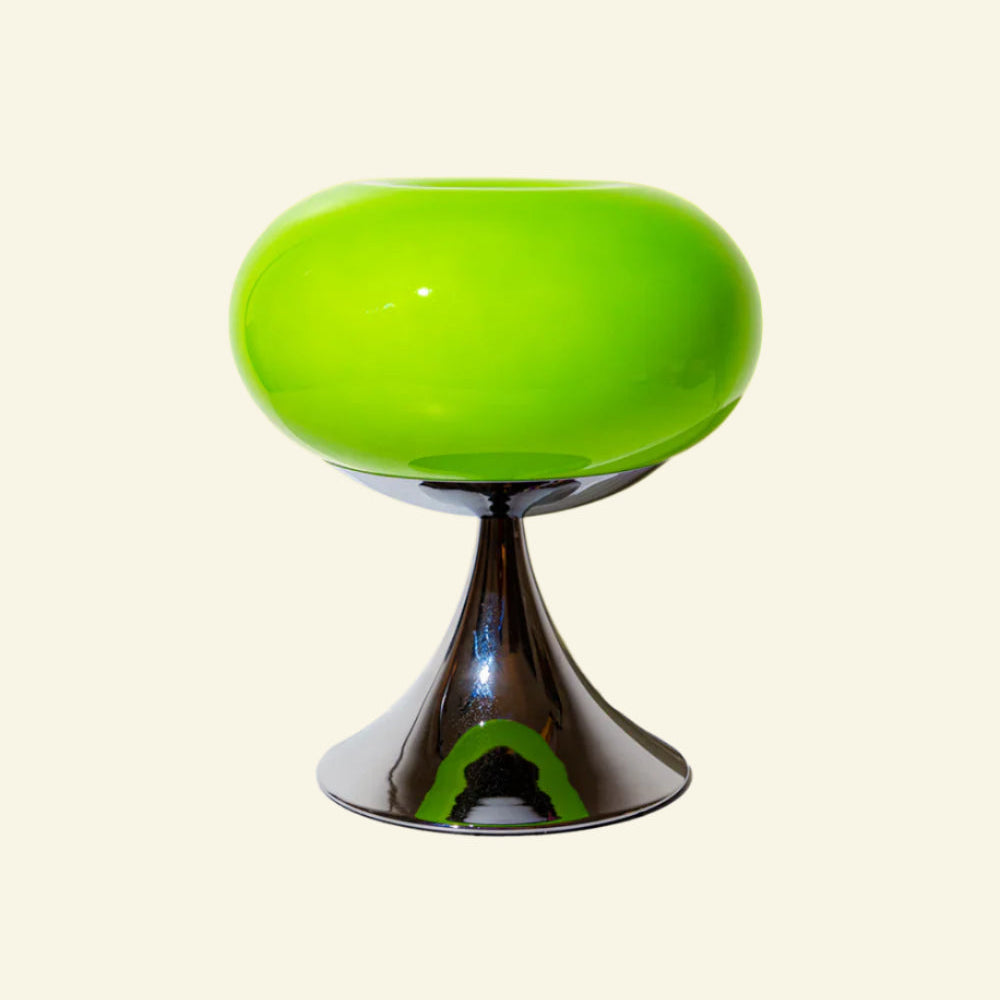 Space age table lamp with glass globe and metal base on beige background.