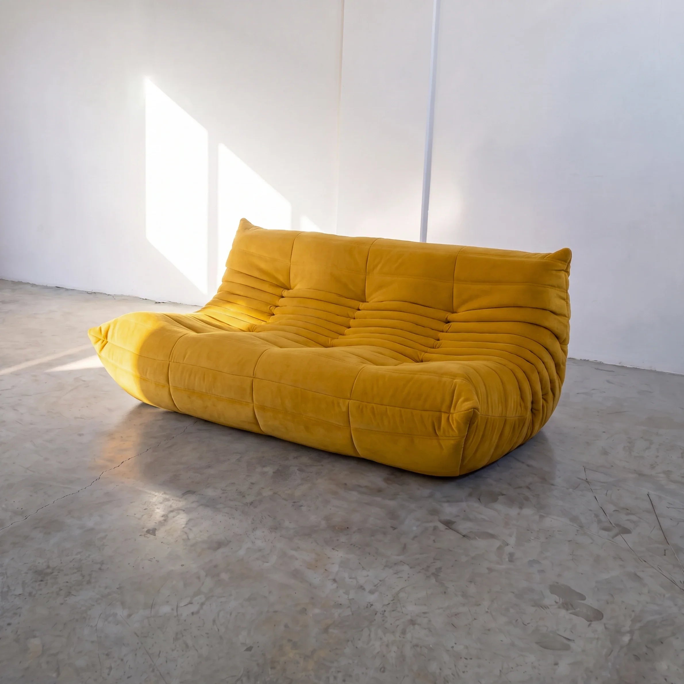 togo sofa dupe 3-seater in yellow velvet shown from an angled front view in a sunlit studio by vibehaus