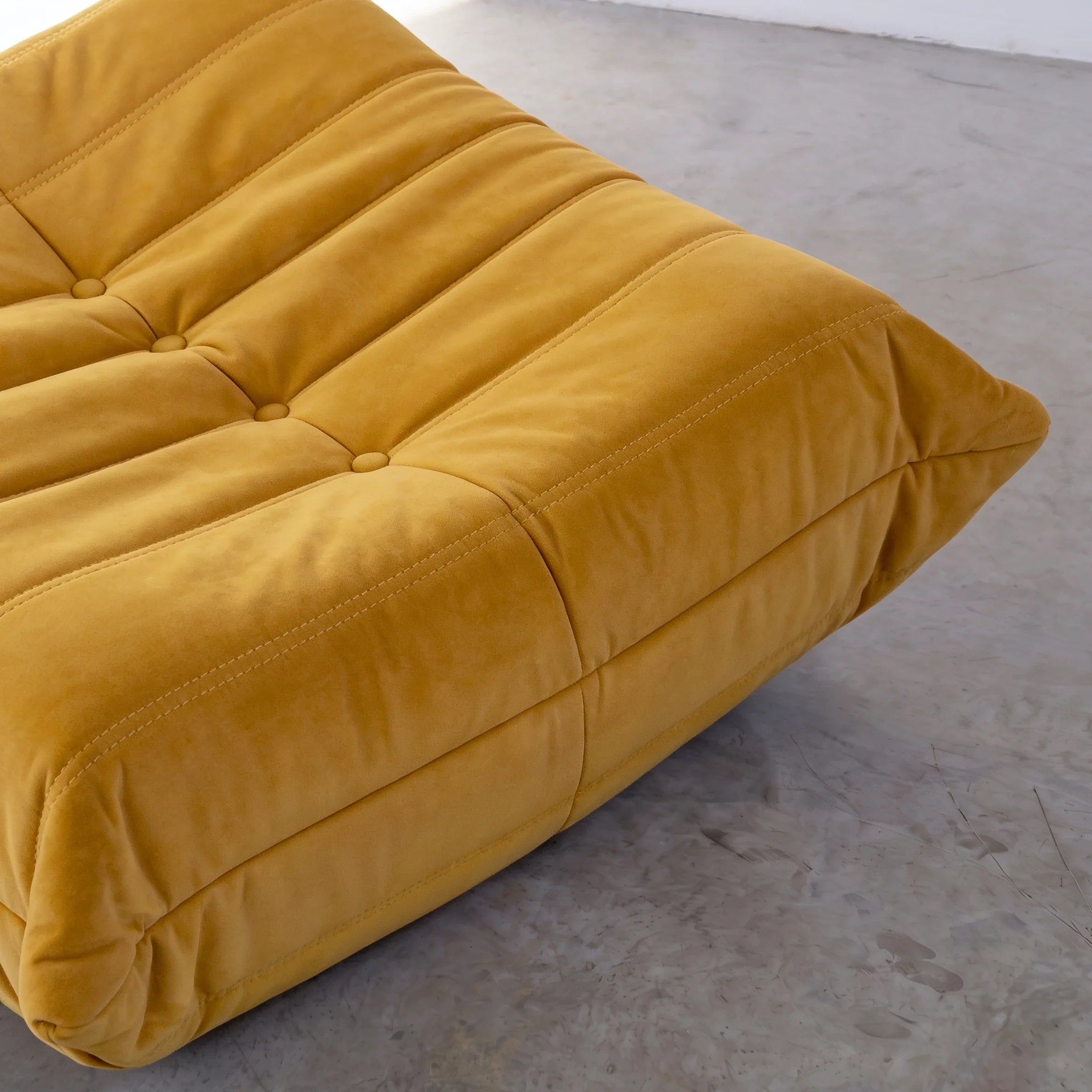 togo sofa dupe ottoman close-up showing the yellow velvet upholstery and tufted stitching by vibehaus