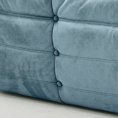 Close-up of a Light Blue Togo Sofa Dupe in Velvet Suede on a concrete floor with a white wall background