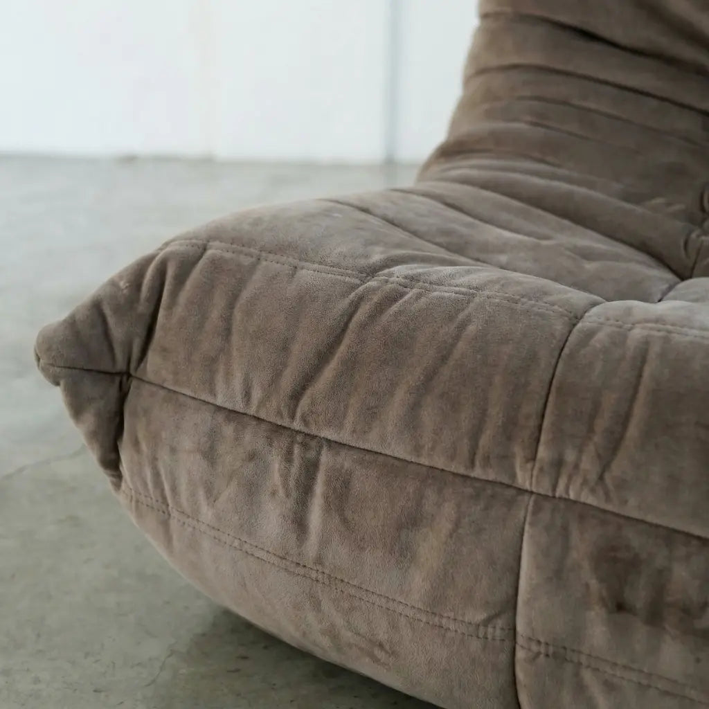 Close-up of a brown togo dupe chair in velvet suede on a light gray floor.