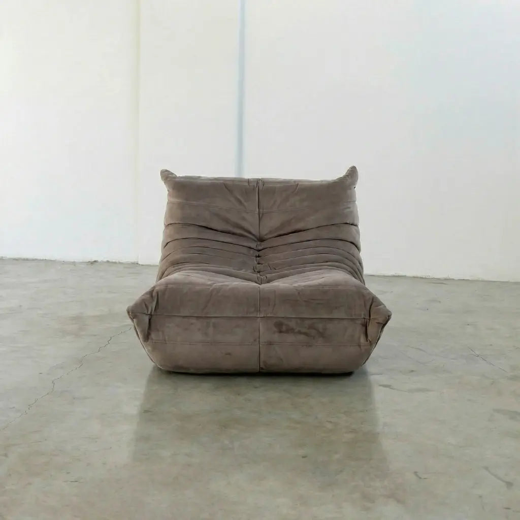 Togo Chair Dupe in taupe, brownish color made from velvet suede by vibehaus, on a concrete floor with a white wall background