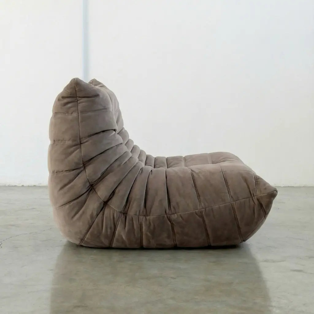 Togo Chair Dupe in taupe, brownish color made from velvet suede by vibehaus, on a concrete floor with a white wall background