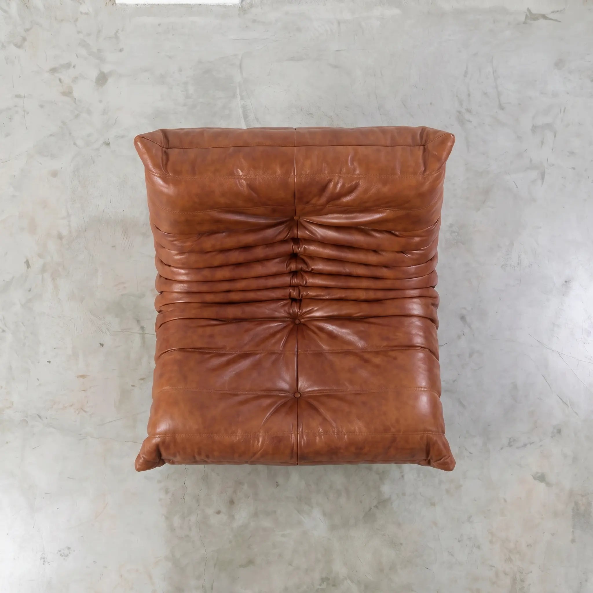 Brown oil waxed leather togo dupe chair on a textured gray surface