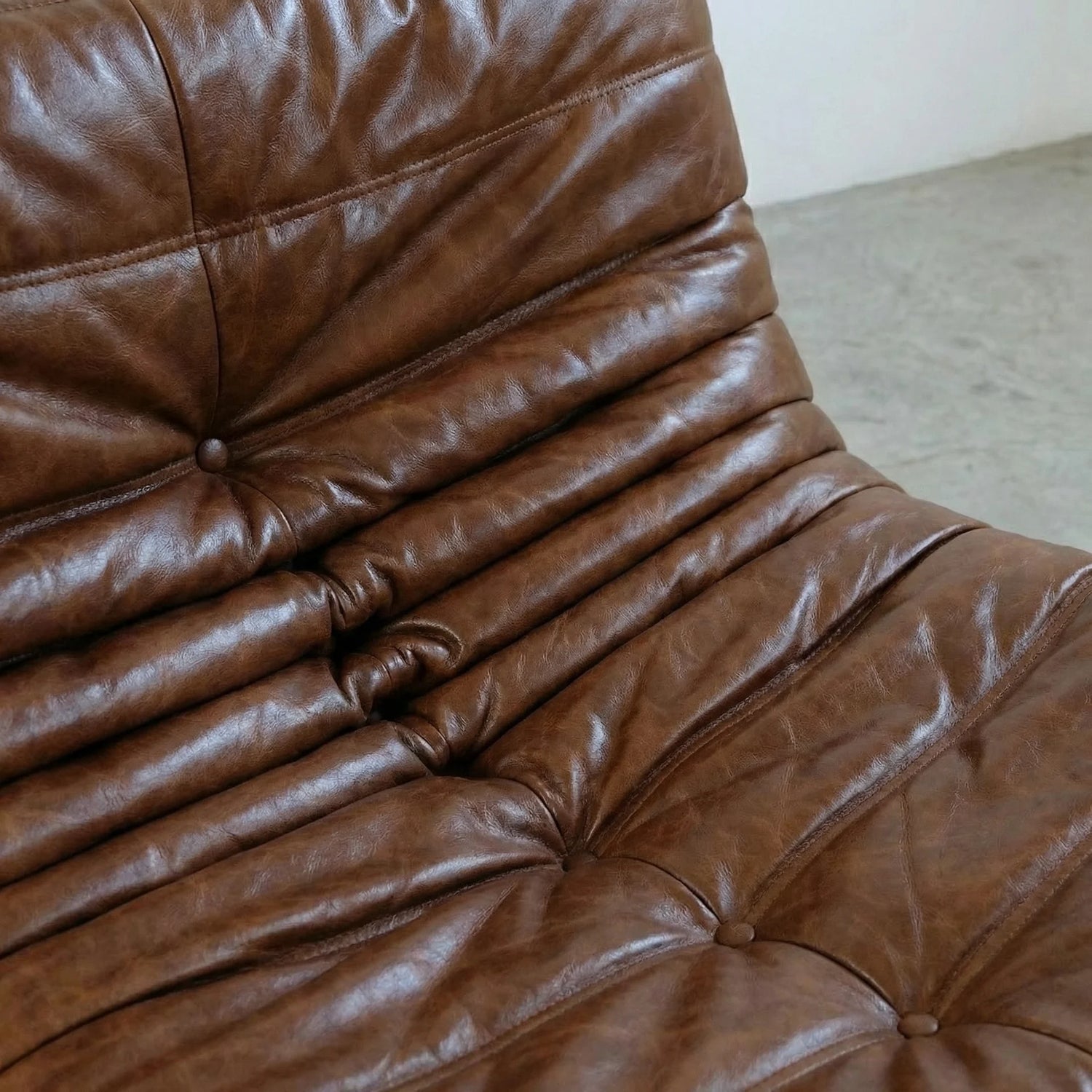 Close-up of a brown togo sofa dupe in leather with visible stitching