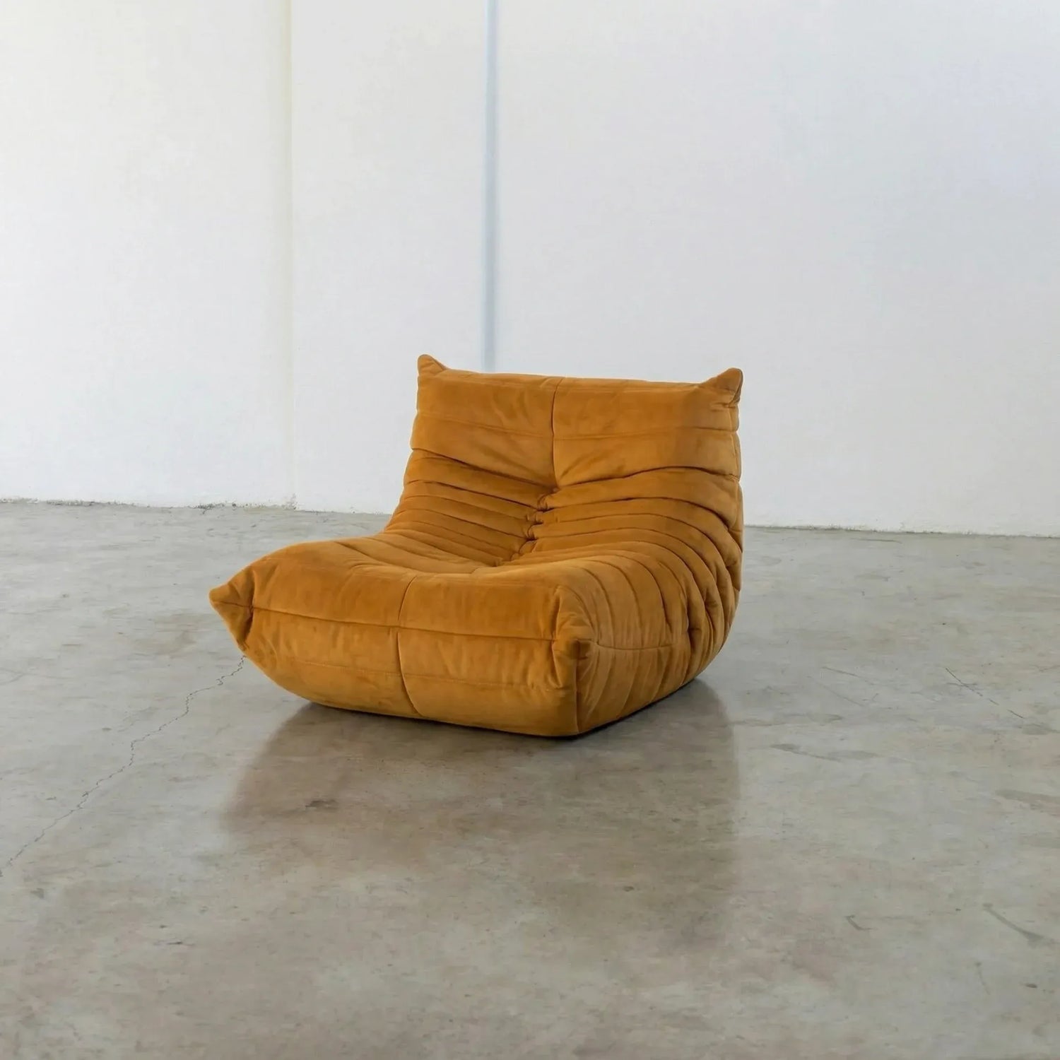 Mustard yellow togo chair dupe on a concrete floor with white walls by vibehaus