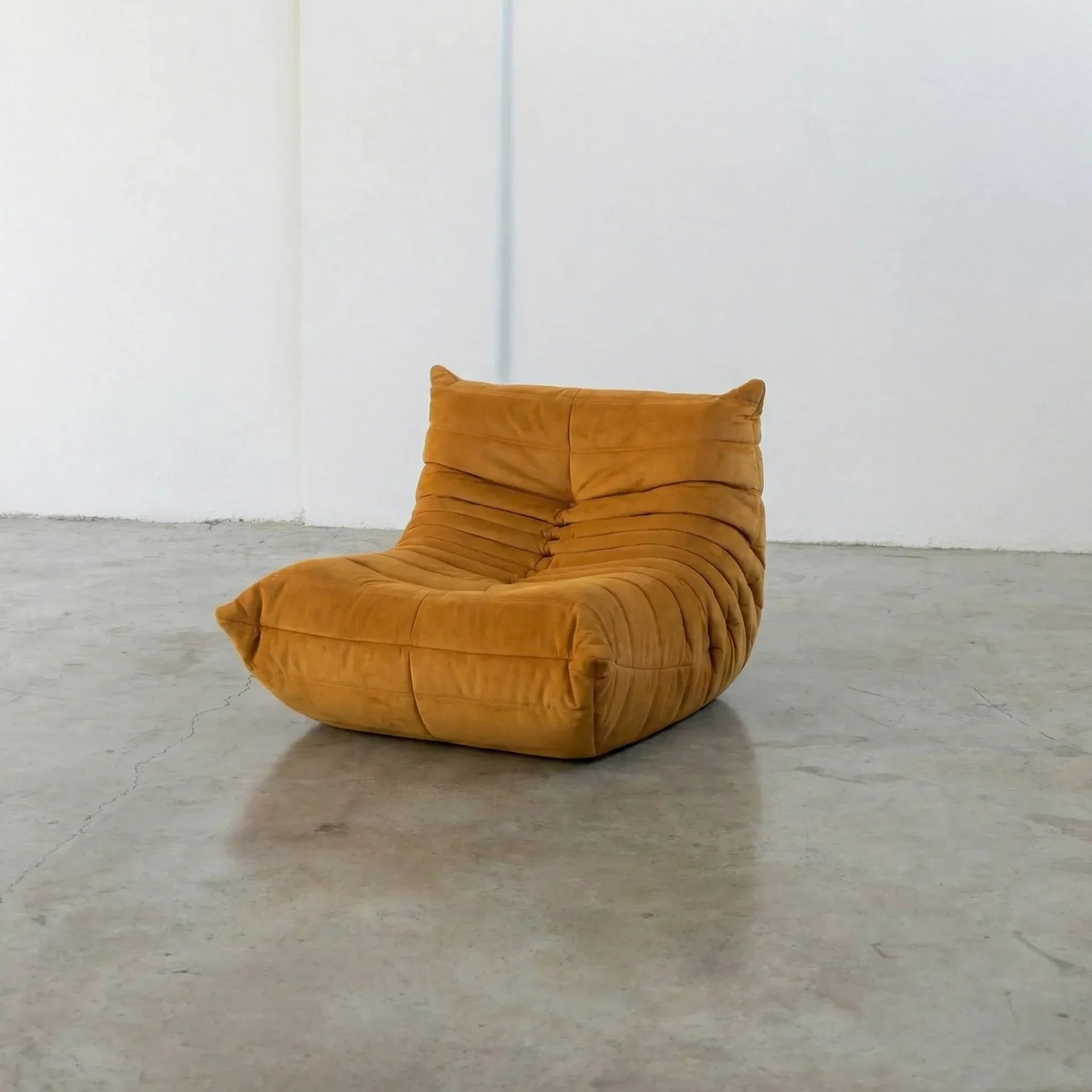 Mustard yellow togo chair dupe on a concrete floor with white walls by vibehaus