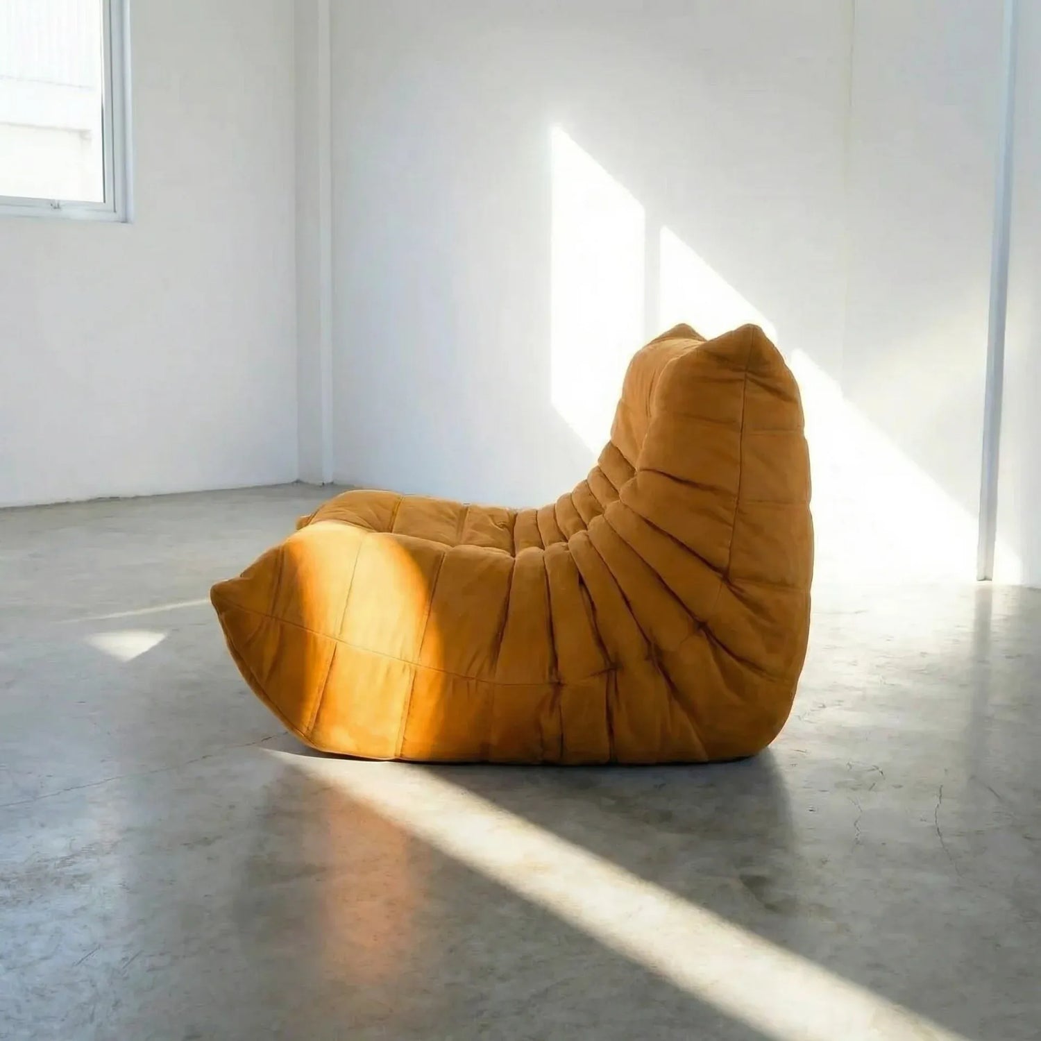 Mustard yellow togo chair dupe on a concrete floor with white walls by vibehaus, shot from the side