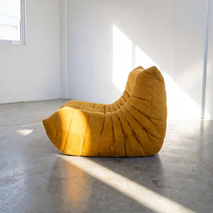Yellow togo chair dupe on a concrete floor with white walls by vibehaus, shot from the side