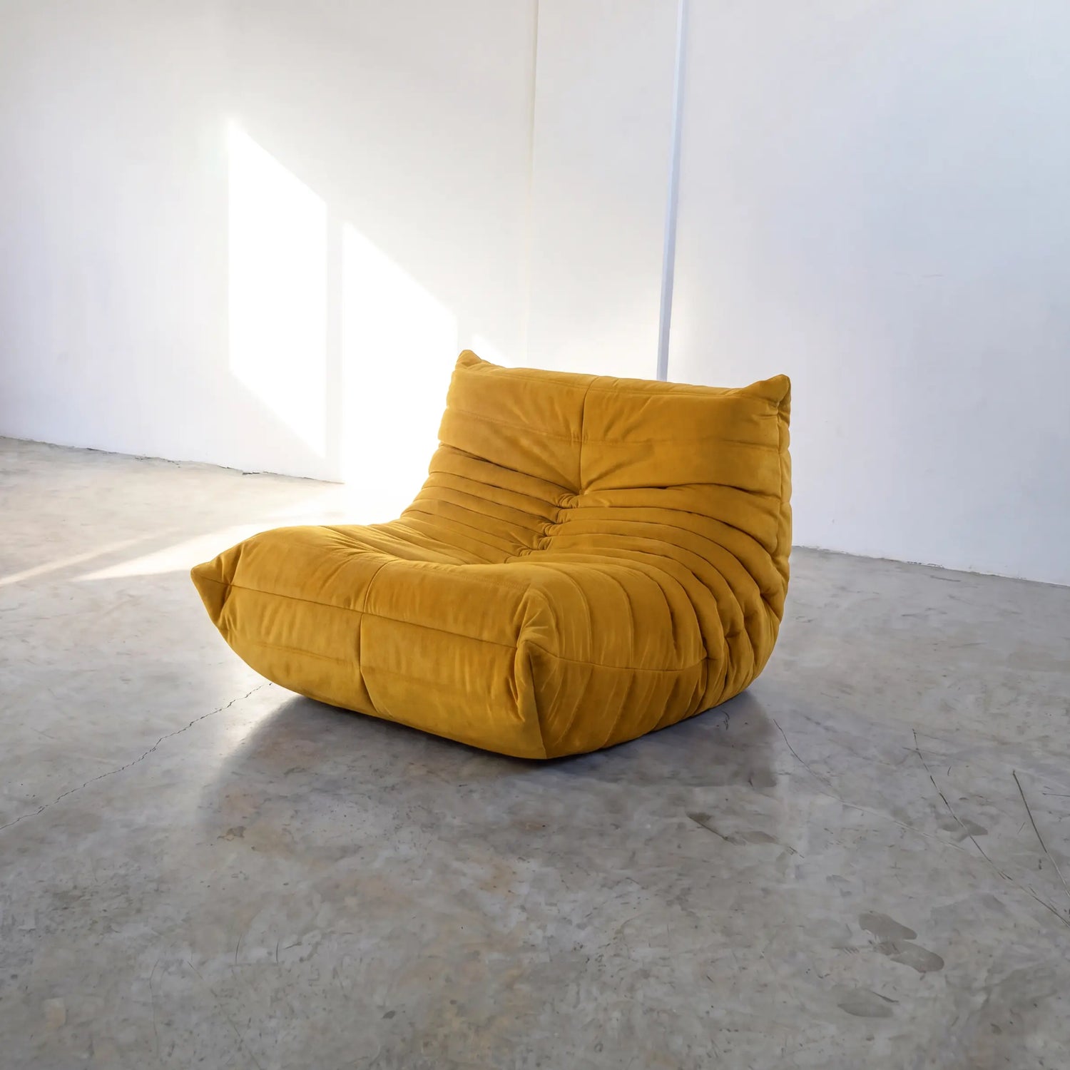yellow togo chair dupe on a concrete floor with white walls by vibehaus
