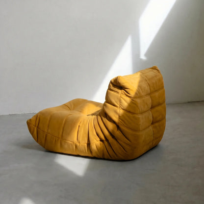 Togo Chair replica in yellow on a concrete floor with white walls by vibehaus