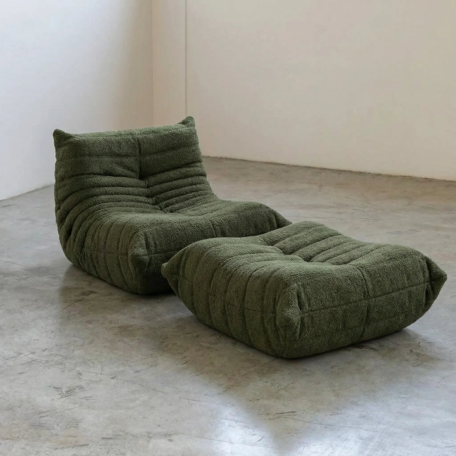 Togo chair and ottoman dupe in Dark Green Bouclé by Vibehaus on a concrete floor