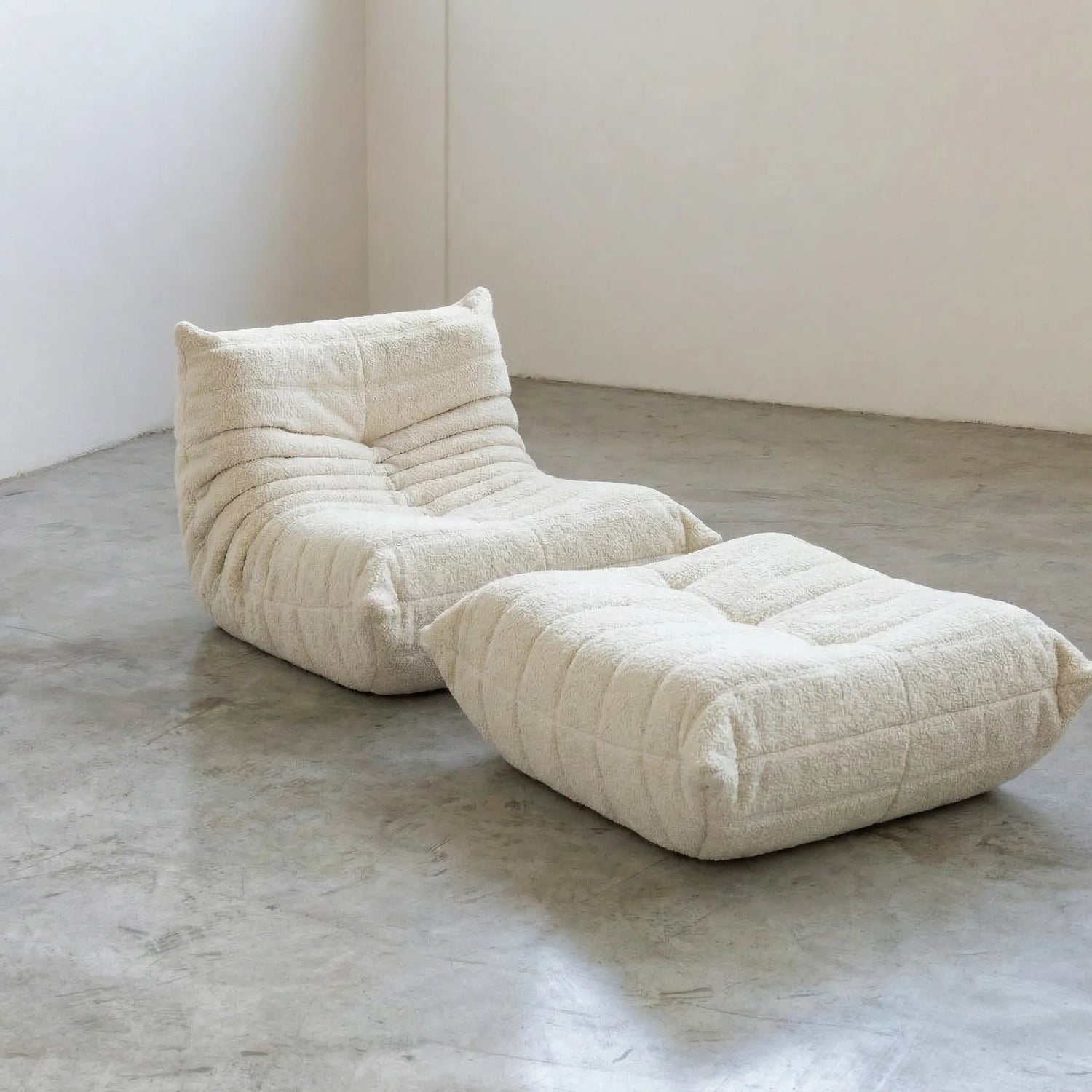 Togo chair and ottoman dupe in White Bouclé by Vibehaus on a concrete floor