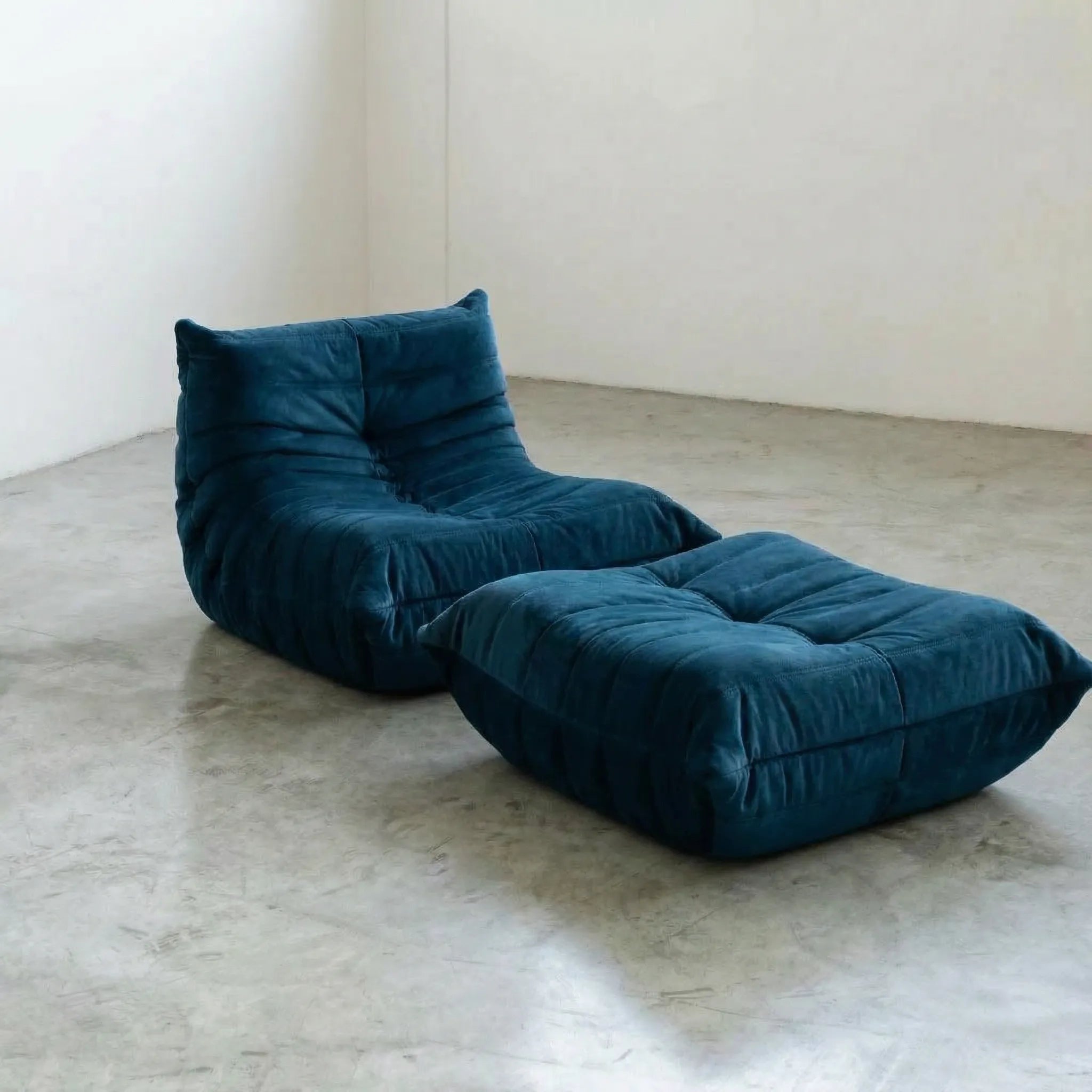 Togo chair and ottoman dupe in Dark Blue Velvet Suede by Vibehaus on a concrete floor