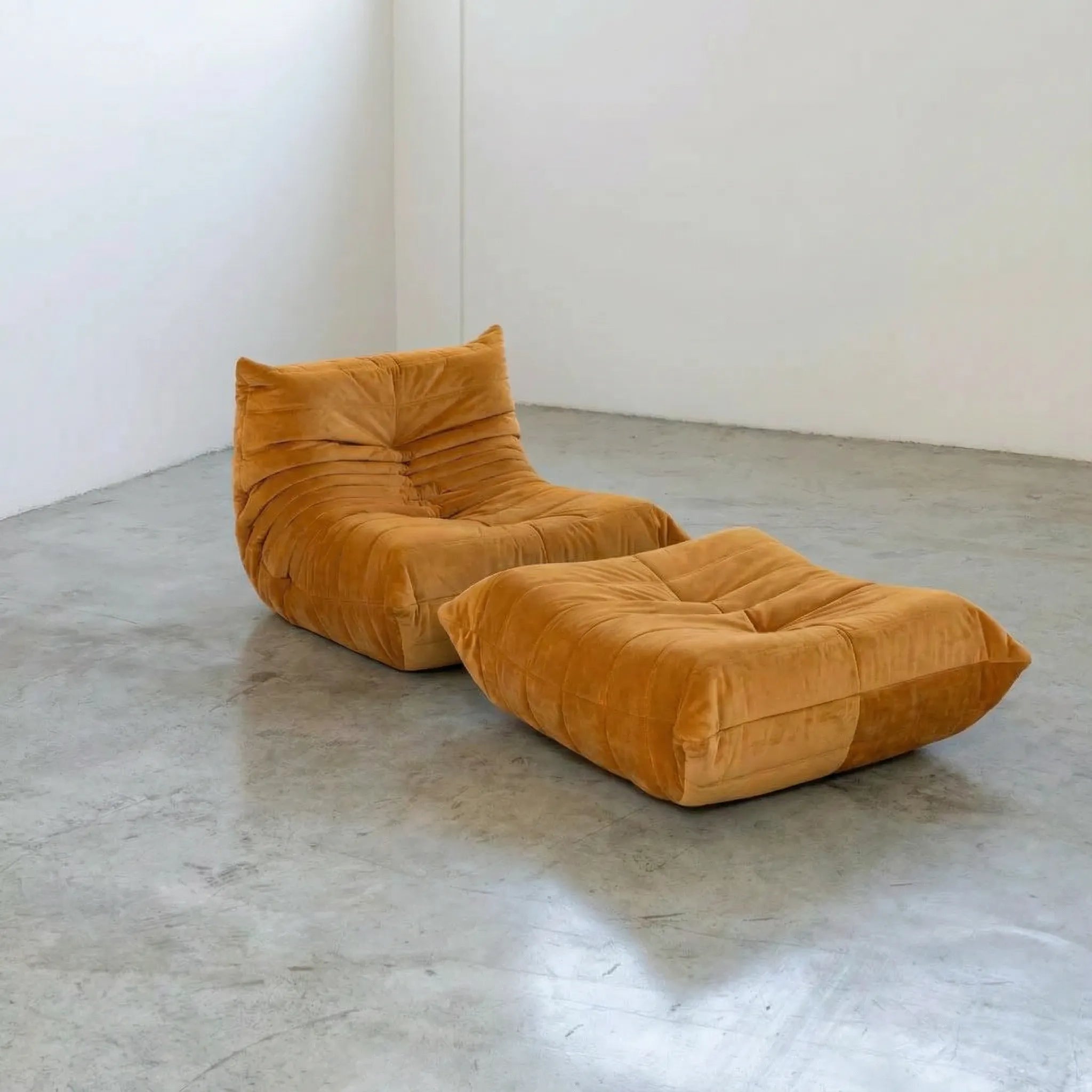 Orange velvet suede Togo chair and ottoman dupe by Vibehaus on a concrete floor