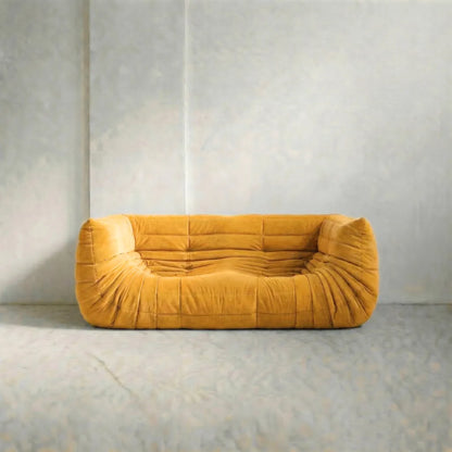Togo Bankreplica in geel met armleuningen op een beige achtergrond op een grijze vloer met een neutrale muurachtergrond