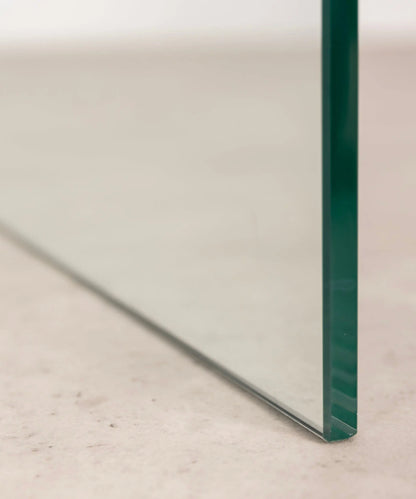 Close-up of the transparent  c-shaped side table against a neutral background