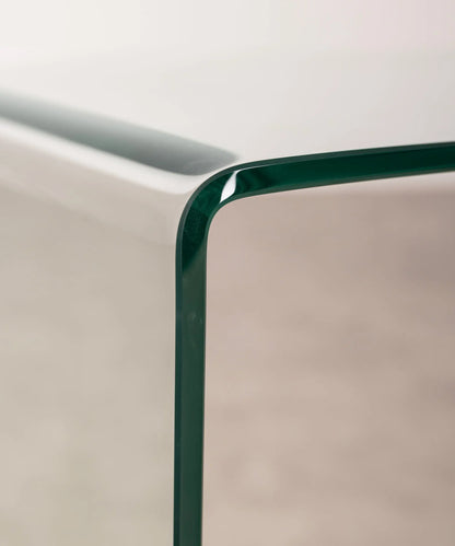 Close-up of the transparent  c-shaped side table against a neutral background