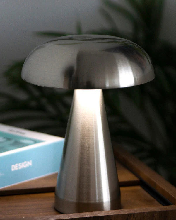 Metallic mushroom table lamp on a wooden surface with a blurred background