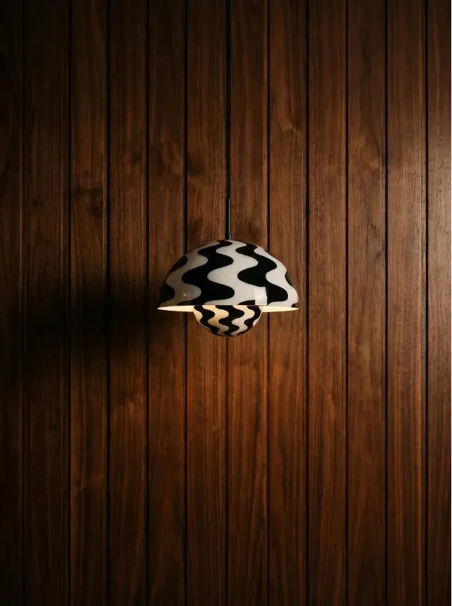 Black and white patterned pendant lamp against a dark wood wall.
