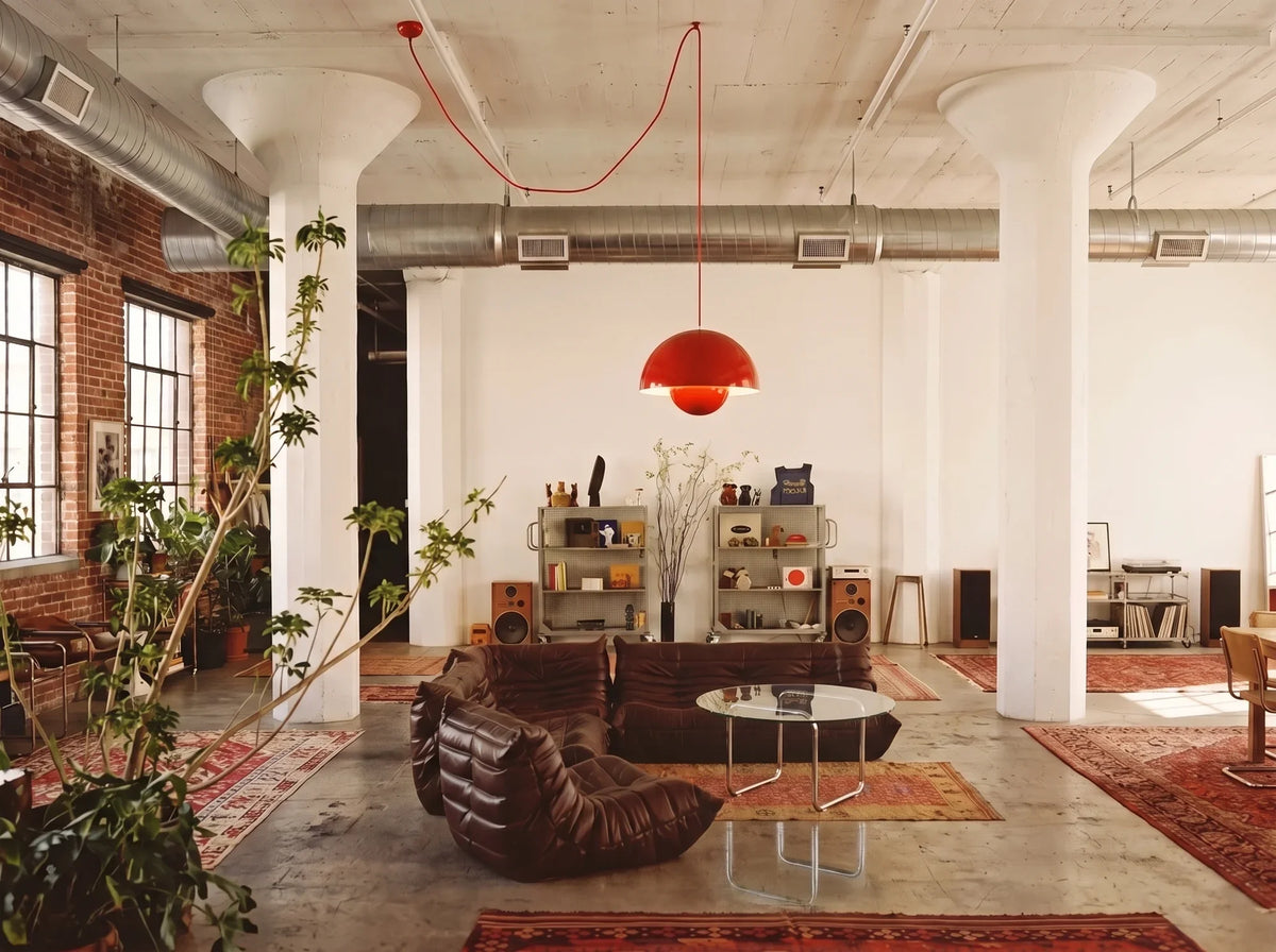 Loft living room with brown quilted lounge chairs, a round coffee table and a red pendant lamp.