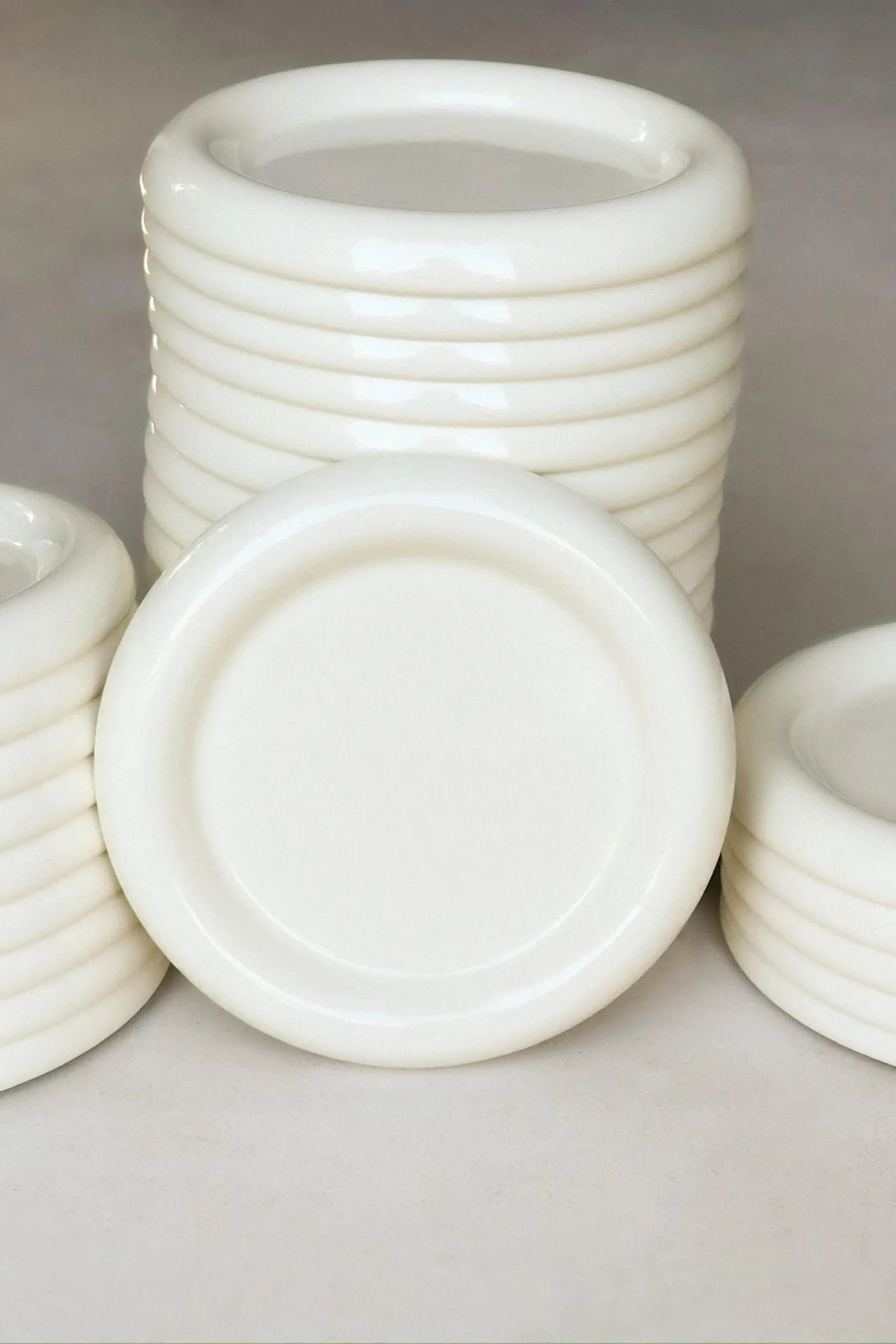 Stack of white chunky ceramic plates inspired by gustaf westman on a gray background