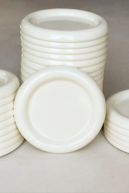 Stack of white chunky ceramic plates inspired by gustaf westman on a gray background